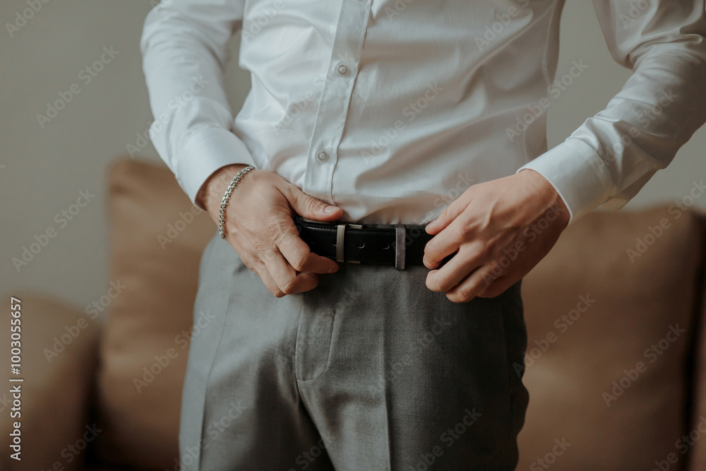 A man in a white shirt is adjusting his belt. Concept of formality and attention to detail A man in a white shirt is adjusting his belt. Concept of formality and attention to detail