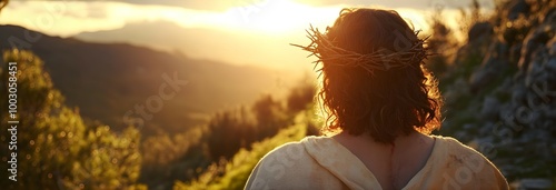 Jesus Christ with a crown of thorns on his head, seen from behind, looking at the sun in a mountainous landscape photo