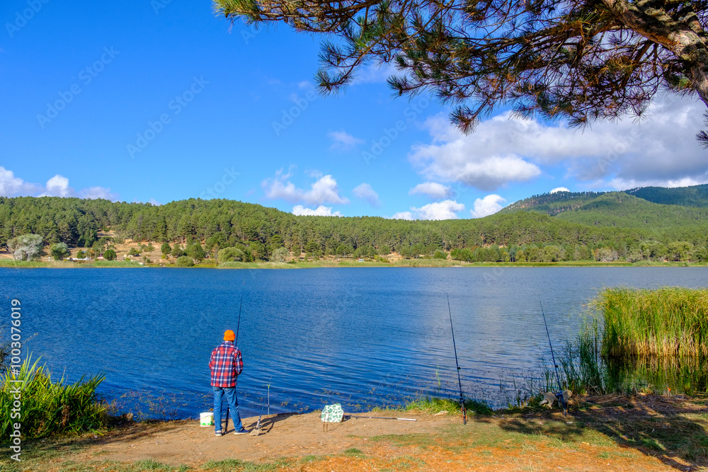 Man relaxing by fishing near the lake in countryside Man relaxing by fishing near the lake in countryside