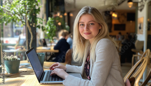 Retrato de uma mulher loira trabalhando remotamente em um laptop em um café. Cultura de trabalho flexível e positiva.