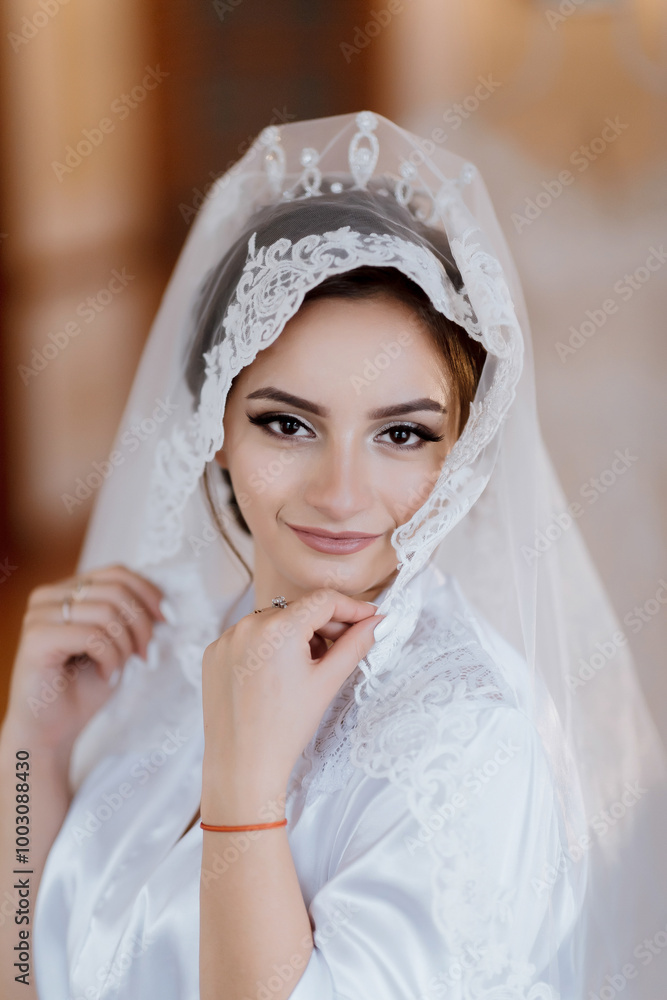 Fototapeta premium A woman wearing a white veil with lace and a red bracelet. She is smiling and looking at the camera