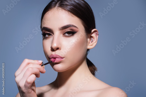 Sexy girl use lipstick, background beauty and fashion, lips appreciation concept. Plump woman lips, isolated on gray studio background.