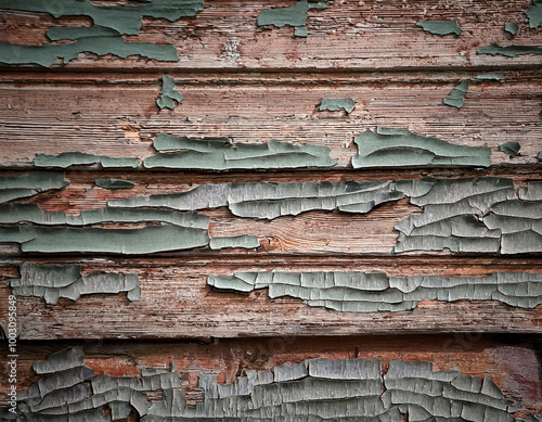 A close-up of cracked, peeling paint on an old wooden wall, revealing the rough texture unde photo