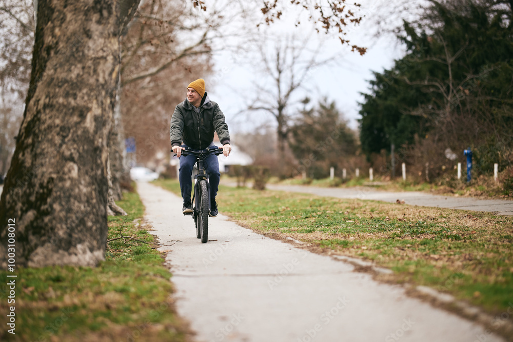 Obraz premium Man Riding Bike Down Street