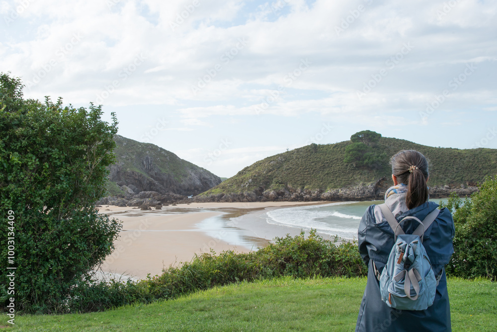 Fototapeta premium Unrecognizable woman looking to Barro beach with no people, in Llanes, Asturias