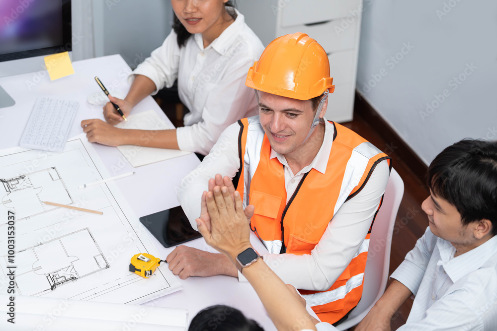 Diverse group of civil engineer and client celebrate and high five after make successful agreement on architectural project, reviewing construction plan and building blueprint at meeting table.Prudent Diverse group of civil engineer and client celebrate and high five after make successful agreement on architectural project, reviewing construction plan and building blueprint at meeting table.Prudent