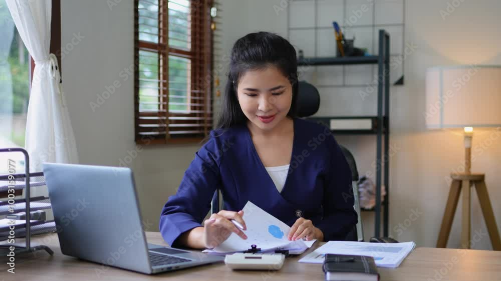 Asian accountant reviewing financial documents at a desk, focused on analysis and utilizing a laptop for data management Asian accountant reviewing financial documents at a desk, focused on analysis and utilizing a laptop for data management
