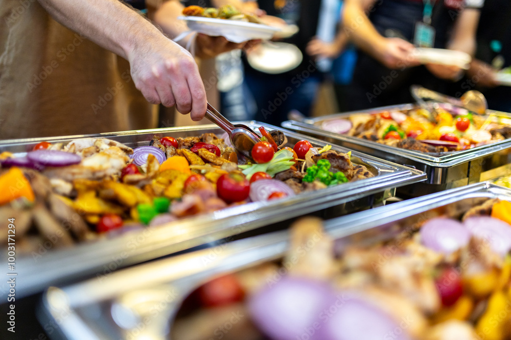 Fototapeta premium Catering at a corporate event with an array of grilled meats and vegetables being served by a guest in a busy, festive atmosphere