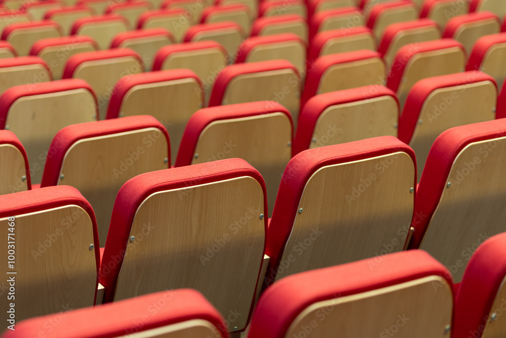 Rows of red and wooden chairs arranged neatly in a large auditorium preparing for an upcoming event or presentation Rows of red and wooden chairs arranged neatly in a large auditorium preparing for an upcoming event or presentation