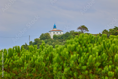 Zumaia Lighthouse behind of green trees, Zumaia, Spain photo