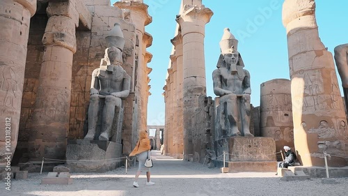 beautiful tourist holding a camera taking pictures of ramsses statue in luxor temple, Luxor, Egypt. photo