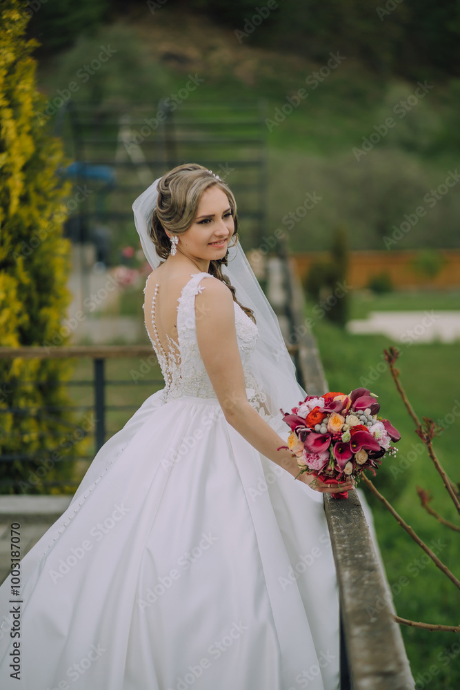 A woman in a white robe stands next to a wedding dress. She is smiling and she is happy A woman in a white robe stands next to a wedding dress. She is smiling and she is happy
