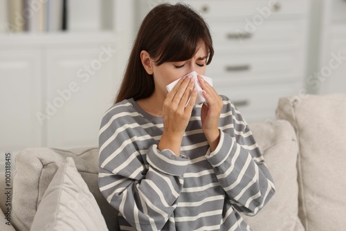 Woman with napkin suffering from sinusitis on sofa at home