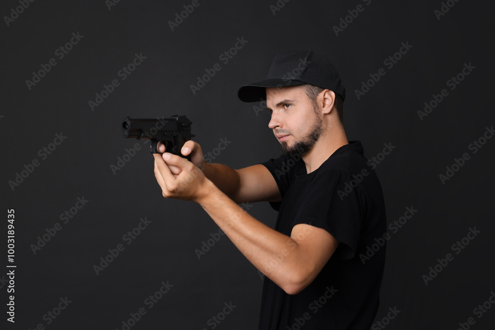 Young bodyguard using gun on black background Young bodyguard using gun on black background