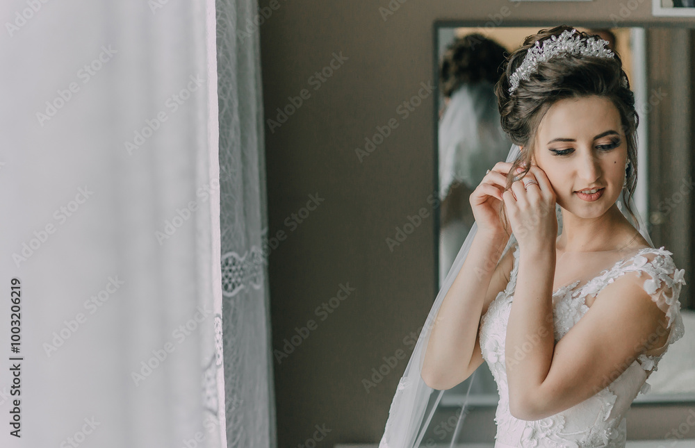 A woman is getting ready for her wedding and is putting on her veil. She is looking at herself in the mirror and she is focused on her appearance A woman is getting ready for her wedding and is putting on her veil. She is looking at herself in the mirror and she is focused on her appearance