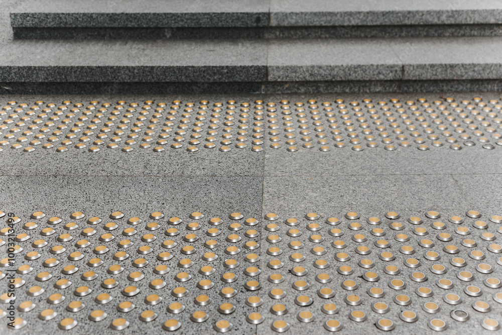 Stainless steel tactile indicators set set on walkway and stairs, closeup. Anti-slip surface.