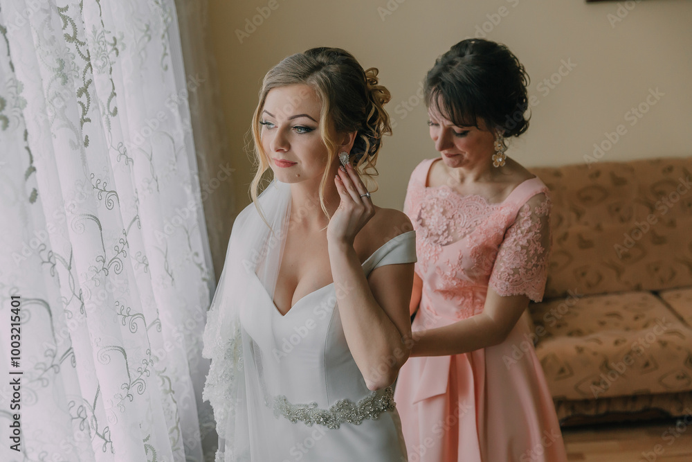 A woman is getting ready for her wedding and her mother is helping her. Scene is one of love and support between the two women A woman is getting ready for her wedding and her mother is helping her. Scene is one of love and support between the two women