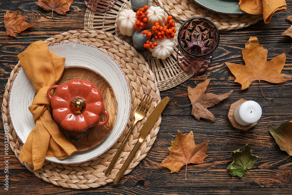 Autumn table serving with pot in shape of pumpkin, golden cutlery and dry leaves on wooden table Autumn table serving with pot in shape of pumpkin, golden cutlery and dry leaves on wooden table