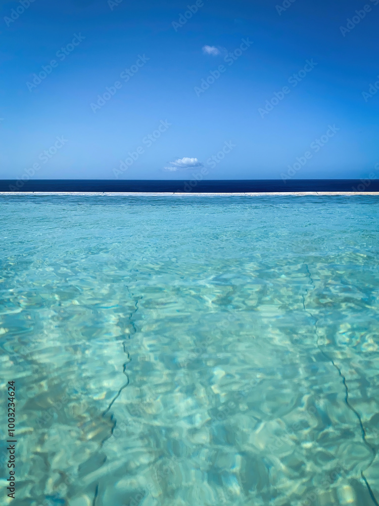 Tiled swimming pool against blue water of Atlantic Ocean and blue sky