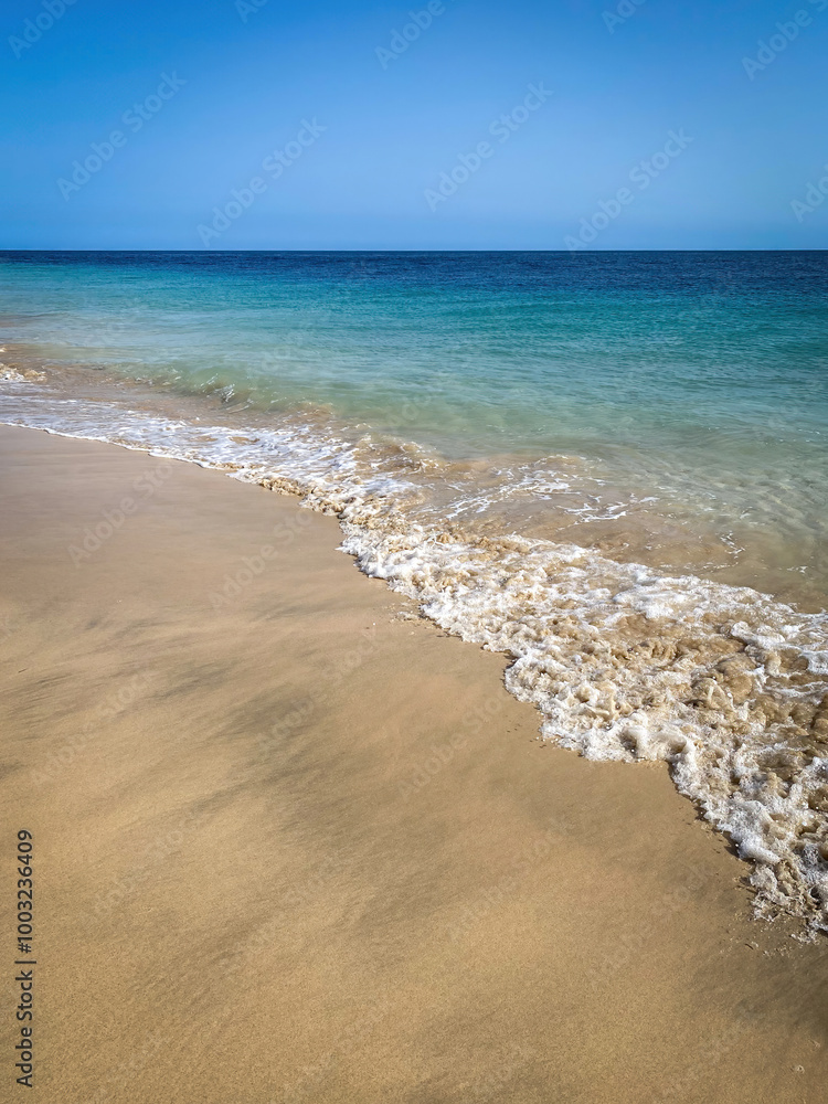 Sandy Atlantic Ocean beach with soft waves against turquoise and blue water and blue sky Sandy Atlantic Ocean beach with soft waves against turquoise and blue water and blue sky