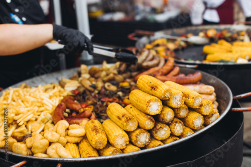 Food festival with food stall kiosk, open-air outdoor fair market, assortment of different traditional European grilled barbecued street food with sausages, bbq, chicken, pork and lamb on a large pan