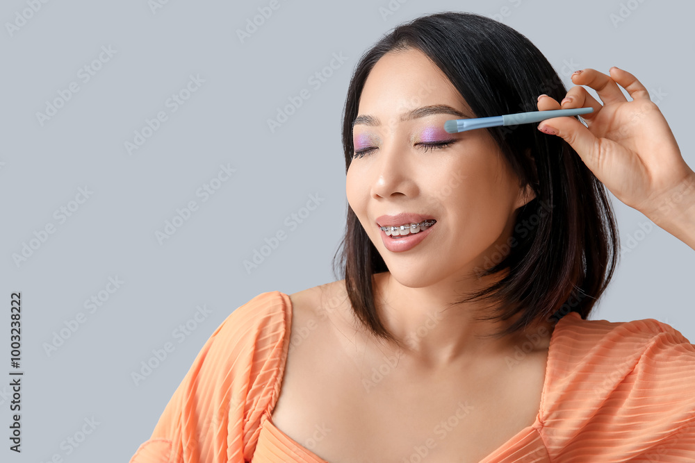 Young Asian woman with makeup brush on white background Young Asian woman with makeup brush on white background