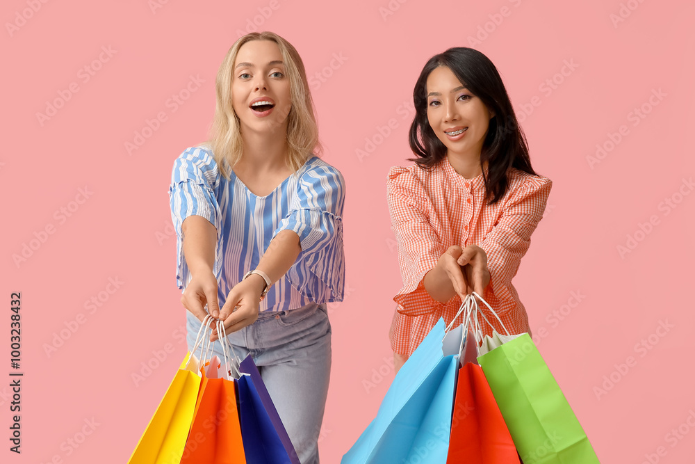 Beautiful young women with shopping bags on pink background Beautiful young women with shopping bags on pink background