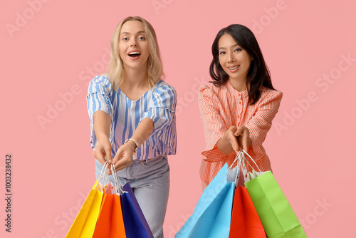 Beautiful young women with shopping bags on pink background