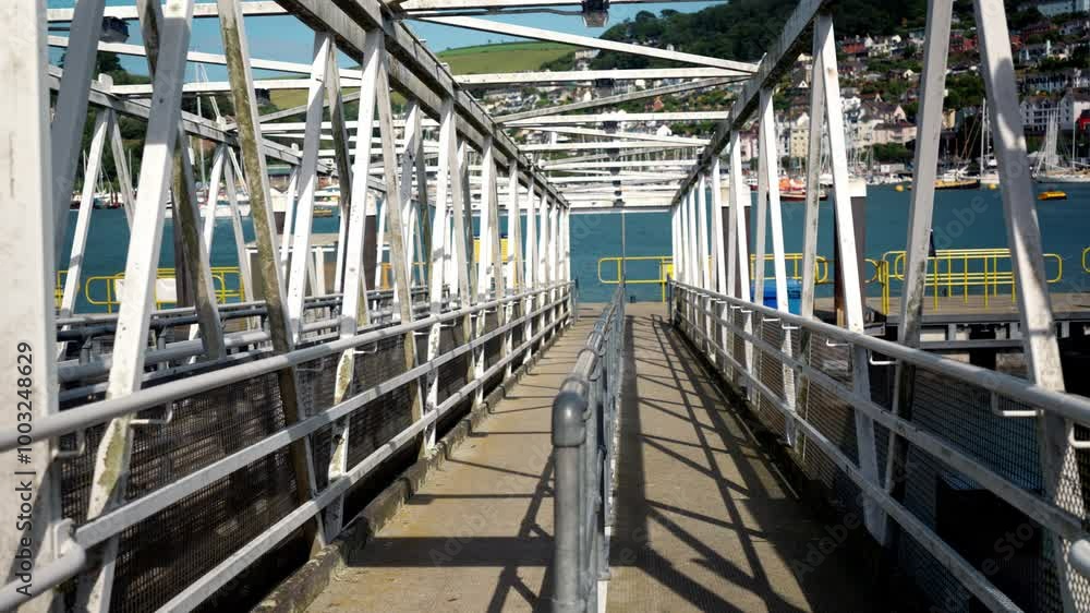 White metal pedestrian bridge leading to boarding of tourist boats. Passage leading to public water transport on a sunny day. White metal pedestrian bridge leading to boarding of tourist boats. Passage leading to public water transport on a sunny day.