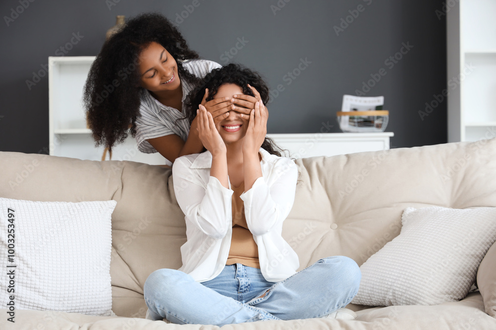 Young African-American girl closing eyes her mother at home Young African-American girl closing eyes her mother at home