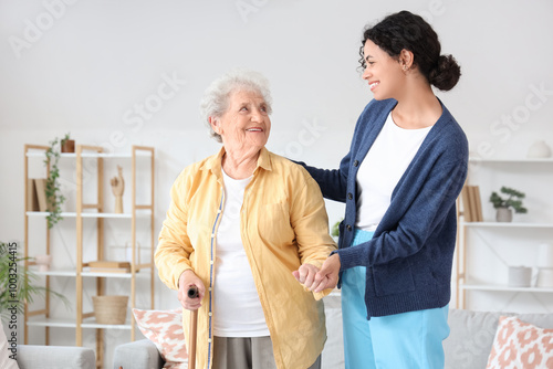 Young African-American female medical worker helping elderly woman in nursing home photo