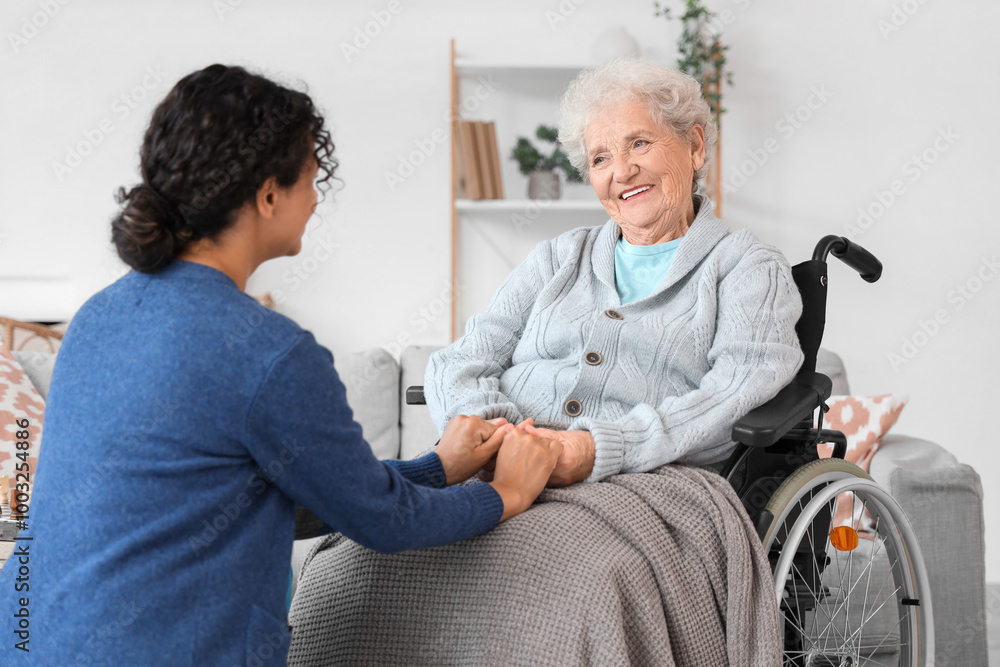 Obraz premium Young African-American female medical worker with elderly woman on wheelchair in nursing home