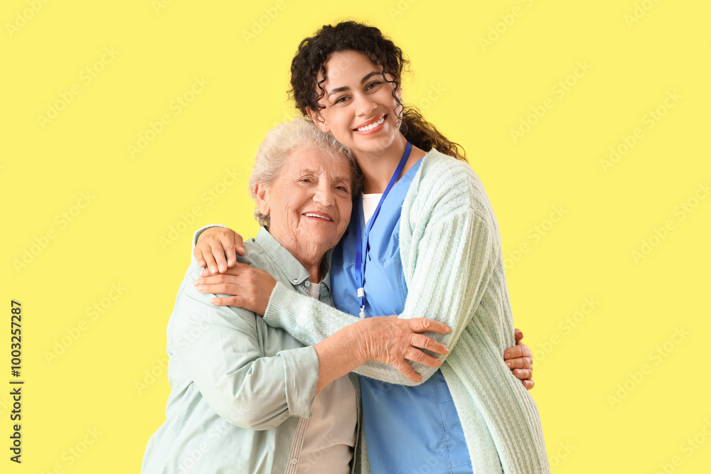 Young African-American female medical worker with elderly woman against yellow background Young African-American female medical worker with elderly woman against yellow background