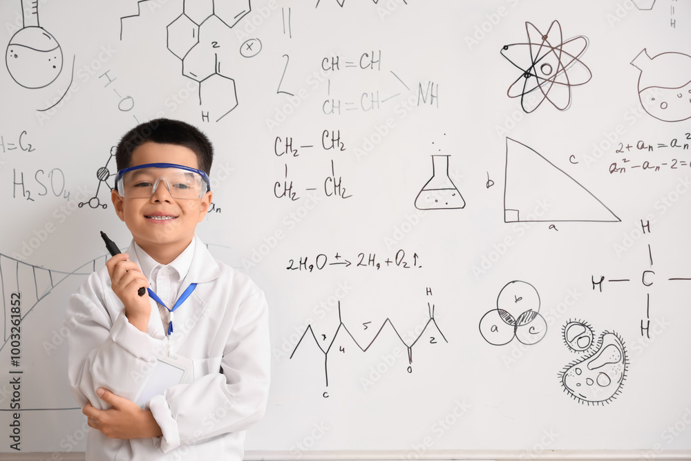 Cute little boy near whiteboard in chemistry classroom Cute little boy near whiteboard in chemistry classroom
