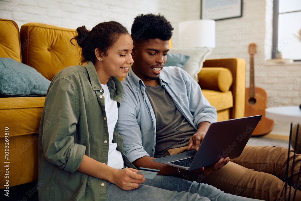 Obraz premium Young happy couple ordering online while using credit card and laptop at home.