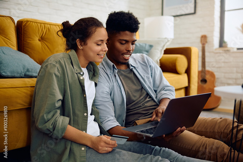 Young happy couple ordering online while using credit card and laptop at home. photo