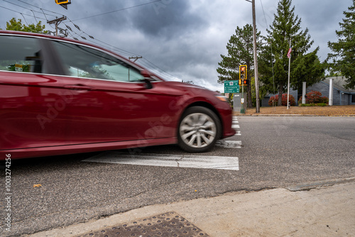 View of a intersection crosswalk as a motion blurred vehicle does a right turn on red