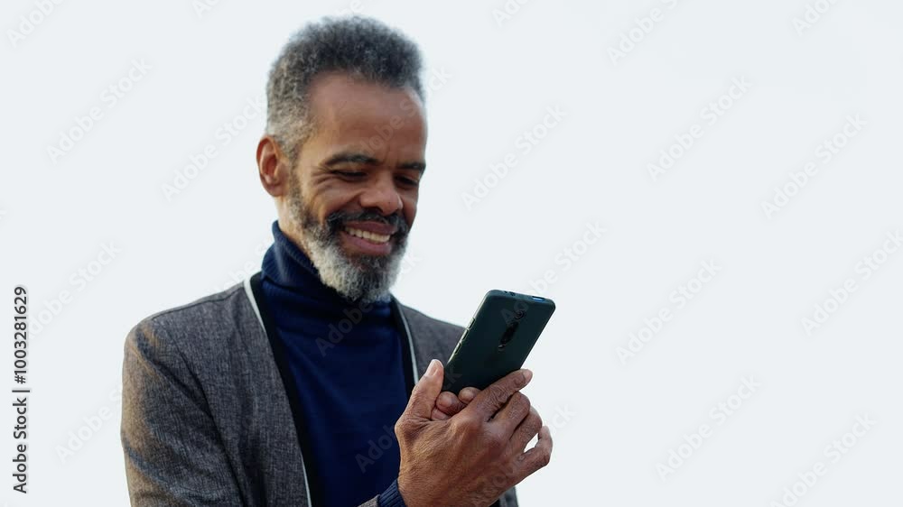 Happy senior black man using mobile phone outside. Old Brazilian male sending online message on cellphone app. Technology and elderly lifestyle concept. Happy senior black man using mobile phone outside. Old Brazilian male sending online message on cellphone app. Technology and elderly lifestyle concept.