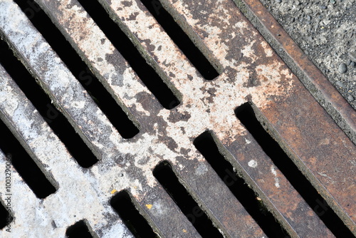 Sewer grate, closeup, stained metal.