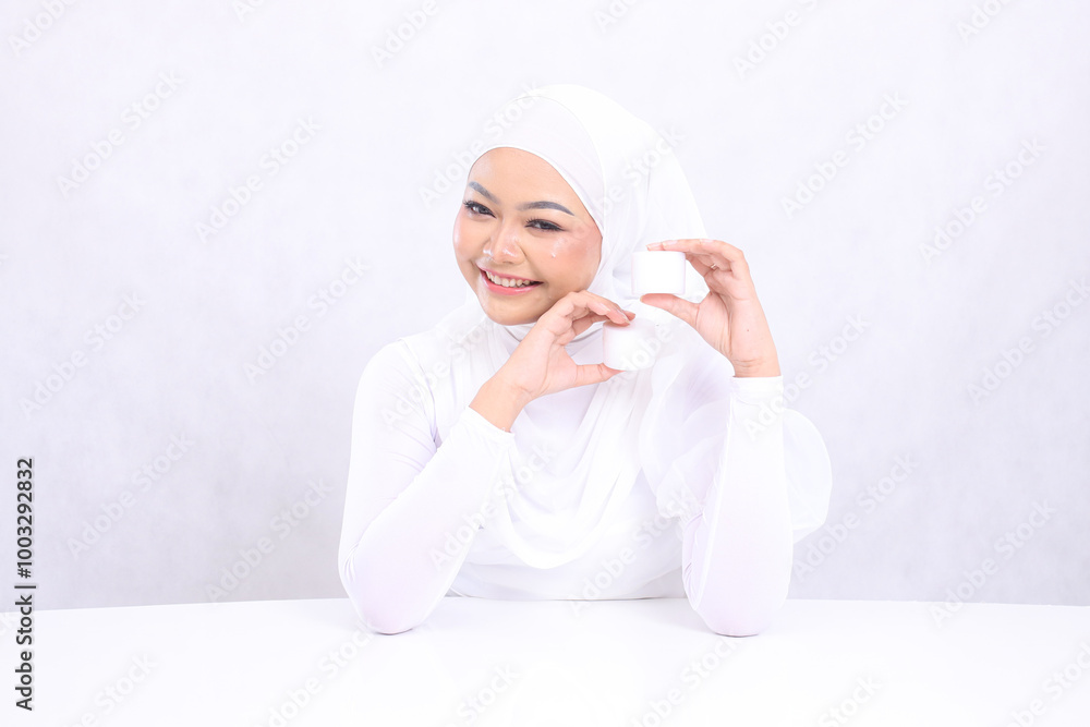 Beauty Beautiful cheerful adult hijab woman asia in front of both hands holding cosmetic cream top and bottom for daily skin care routine needs on white background. Facial treatment, Perfect skin Beauty Beautiful cheerful adult hijab woman asia in front of both hands holding cosmetic cream top and bottom for daily skin care routine needs on white background. Facial treatment, Perfect skin