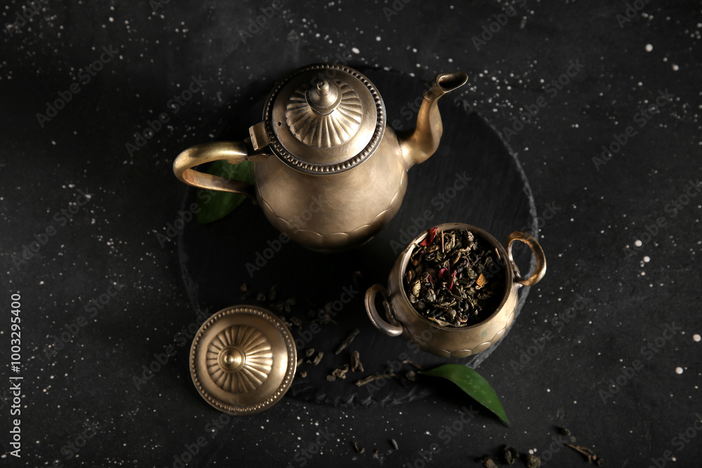 Tray with stylish tea pot and bowl of dry tea on dark background Tray with stylish tea pot and bowl of dry tea on dark background