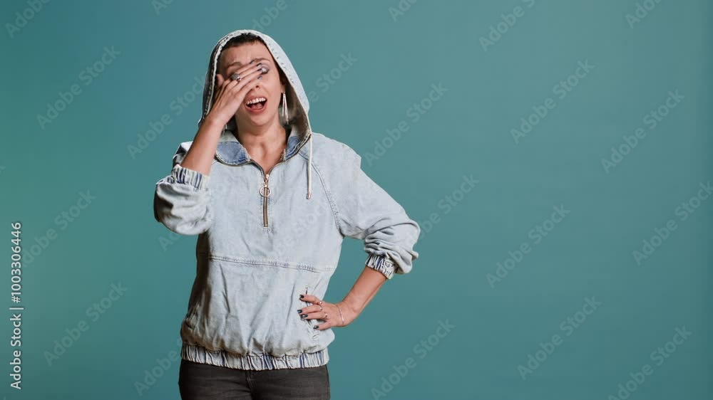 Young woman with a groovy style yawning against blue background, feeling very tired and fatigued. Female model with a fashionable street outfit being sleepy in studio. Camera B. Young woman with a groovy style yawning against blue background, feeling very tired and fatigued. Female model with a fashionable street outfit being sleepy in studio. Camera B.