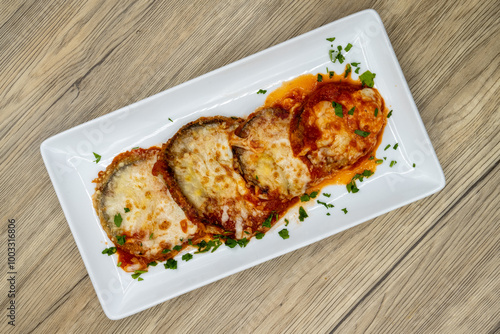 Overhead view of eggplant parmesan and mozzarella cheese served on a plate and cooked to perfection