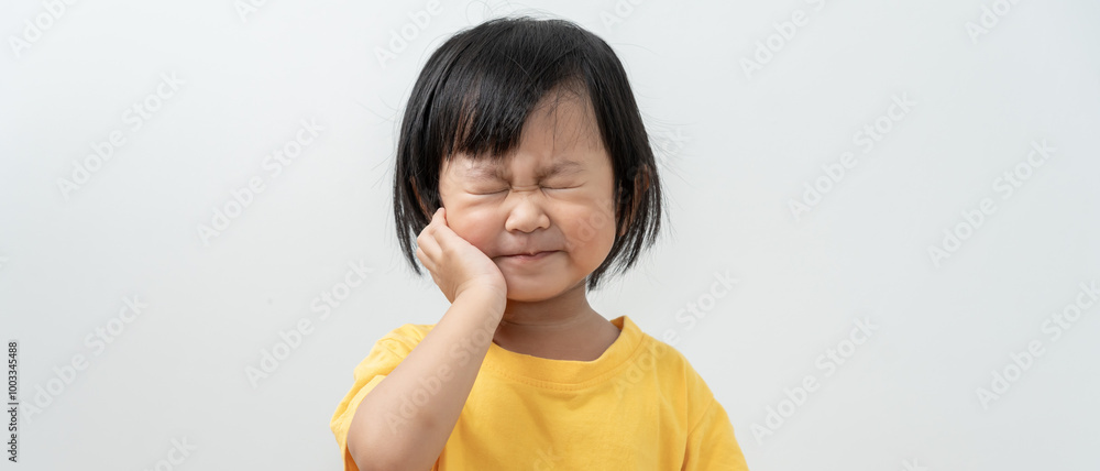 little asian girl presses hand to cheek, suffers from pain in tooth. Teeth decay, dental problems, child emotions and facial expression, oral health care, reducing sweets, fluorine coating little asian girl presses hand to cheek, suffers from pain in tooth. Teeth decay, dental problems, child emotions and facial expression, oral health care, reducing sweets, fluorine coating