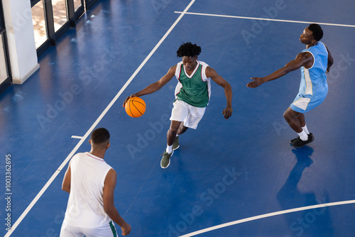 Playing basketball, three African American men in action on indoor court, dribbling and defending photo