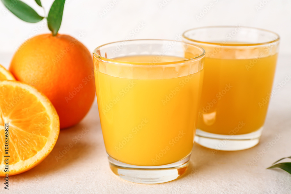 Glasses of fresh orange juice and leaves on white background Glasses of fresh orange juice and leaves on white background