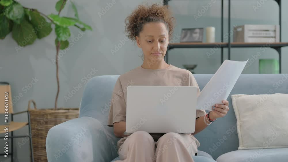Hispanic Woman Doing Paperwork while Sitting on Sofa at Home Hispanic Woman Doing Paperwork while Sitting on Sofa at Home