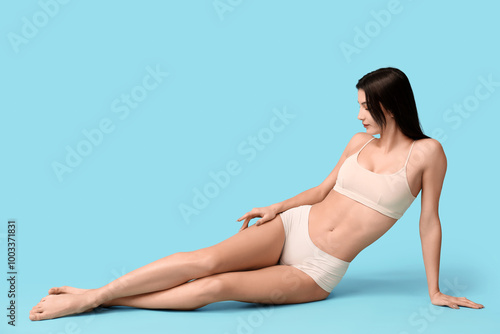 Beautiful young woman sitting on blue background