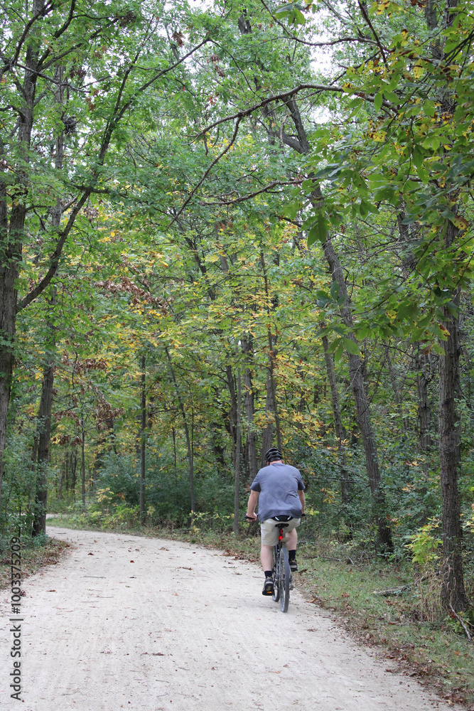 Fototapeta premium Overweight man riding a bicycle in autumn on the Des Plaines River Trail in Libertyville, Illinois