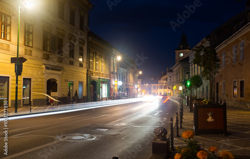 View of illuminated Brasov streets with clock tower of city Council at night